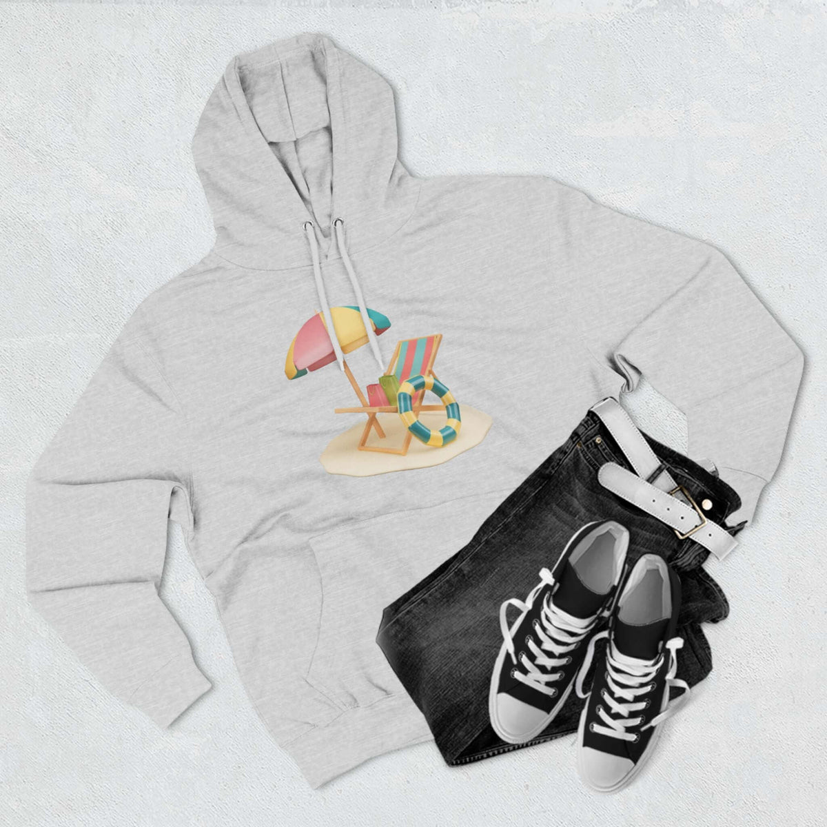 Gray Sunny Resort Hoodie displayed with beach chair graphic, paired with black jeans and sneakers.