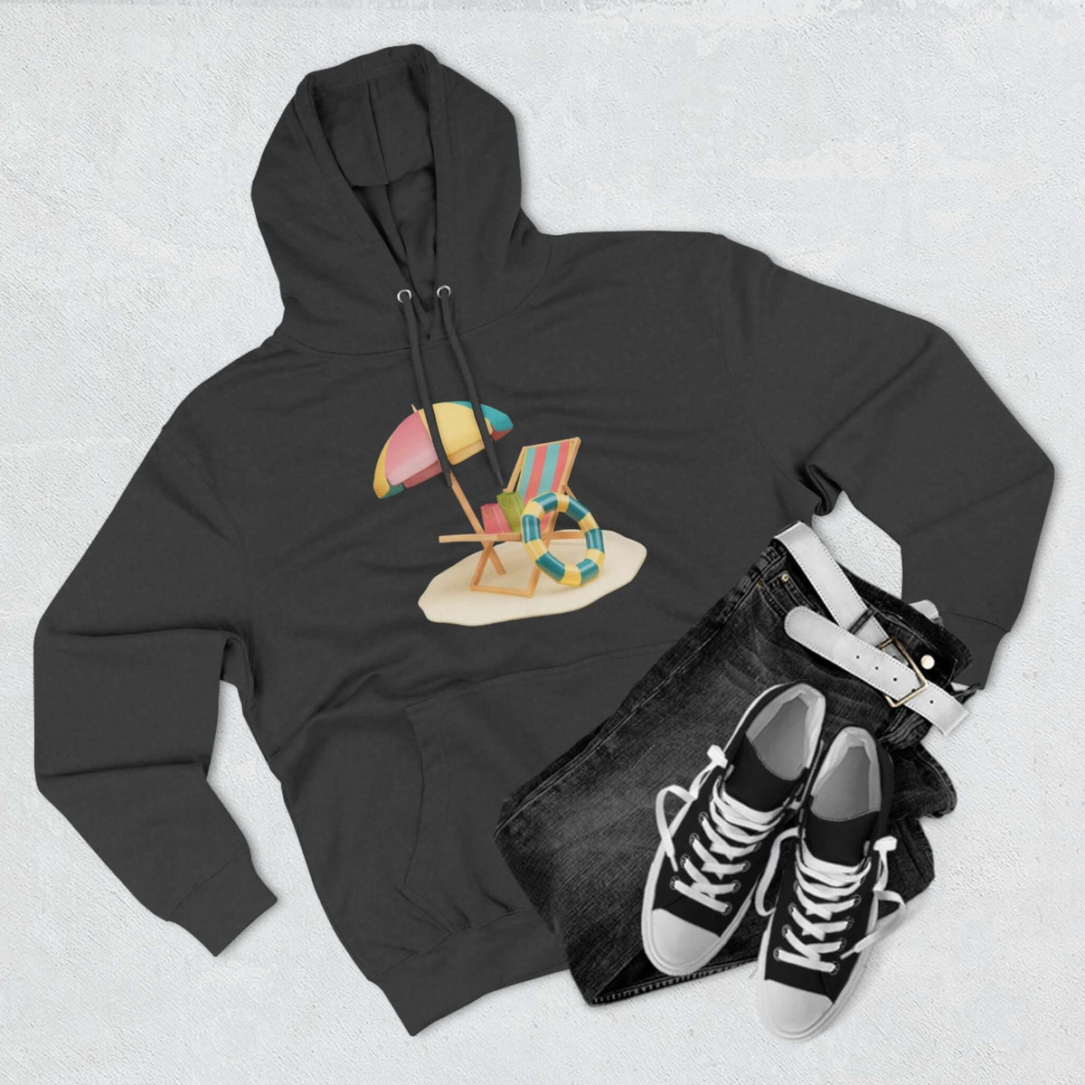 Cozy black hoodie featuring a beach scene design with a chair, umbrella, and colorful beach gear. Perfect for relaxed lounging.