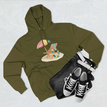 Olive green hoodie featuring beach chair and umbrella graphic, styled with jeans and sneakers. Perfect for relaxed summer vibes.